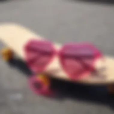 A close-up of hot pink heart sunglasses resting on a skateboard deck